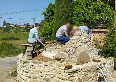 Je réalise un chantier participatif avec Maison Paysanne pour la réalisation d'un four à pain, je tartine des briques avec de l'argile